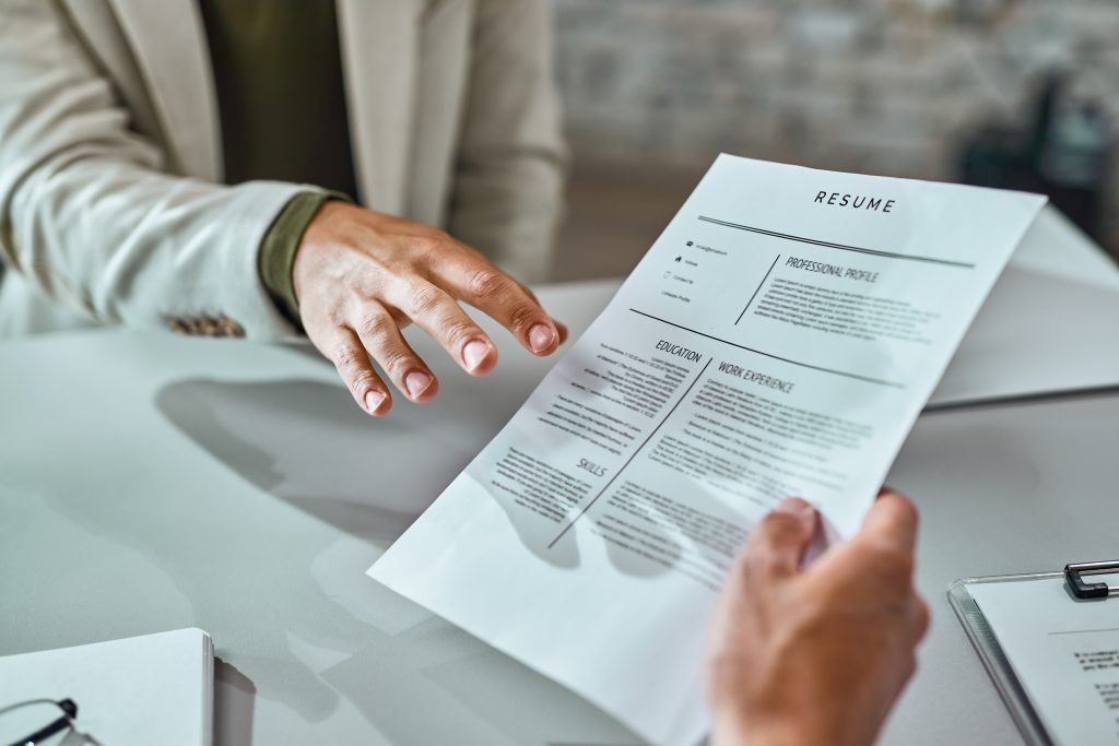 Close-up of a candidate giving his CV while applying for a job in the office.