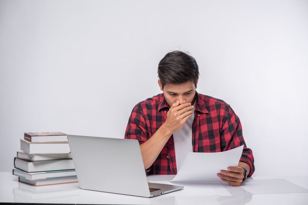 A man using a laptop in the office and doing a document analysis
