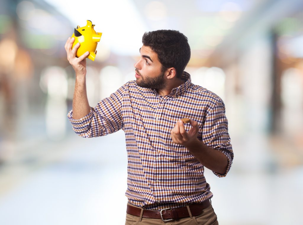 portrait of a handsome man looking into a piggy bank without investment how to start business